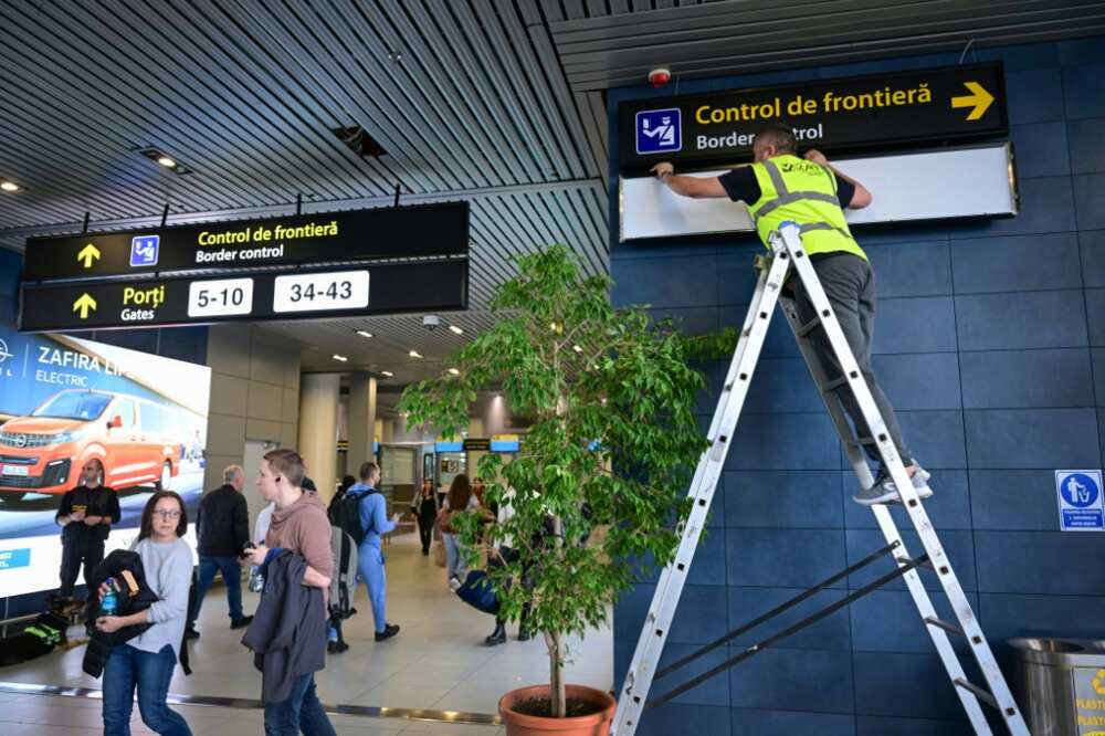 Un muncitor român schimbă semnele pentru călători pe Aeroportul Internațional Henri Coanda înainte ca România și Bulgaria să facă duminică primul pas către zona de călătorie fără viză Schengen.