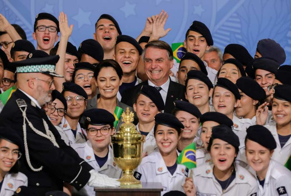 Brazil's President Jair Bolsonaro (C-R) and First Lady Michelle Bolsonaro are surrounded by children as they stand next to an urn containing the embalmed heart of Dom Pedro I, founder and first ruler of the Empire of Brazil, during a ceremony at in Brasilia, on August 23, 2022