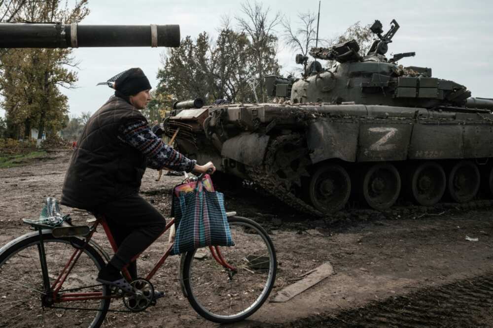 A local resident rides past an abandoned Russian tank marked Z near Kharkiv in Ukraine on September 30, 2022