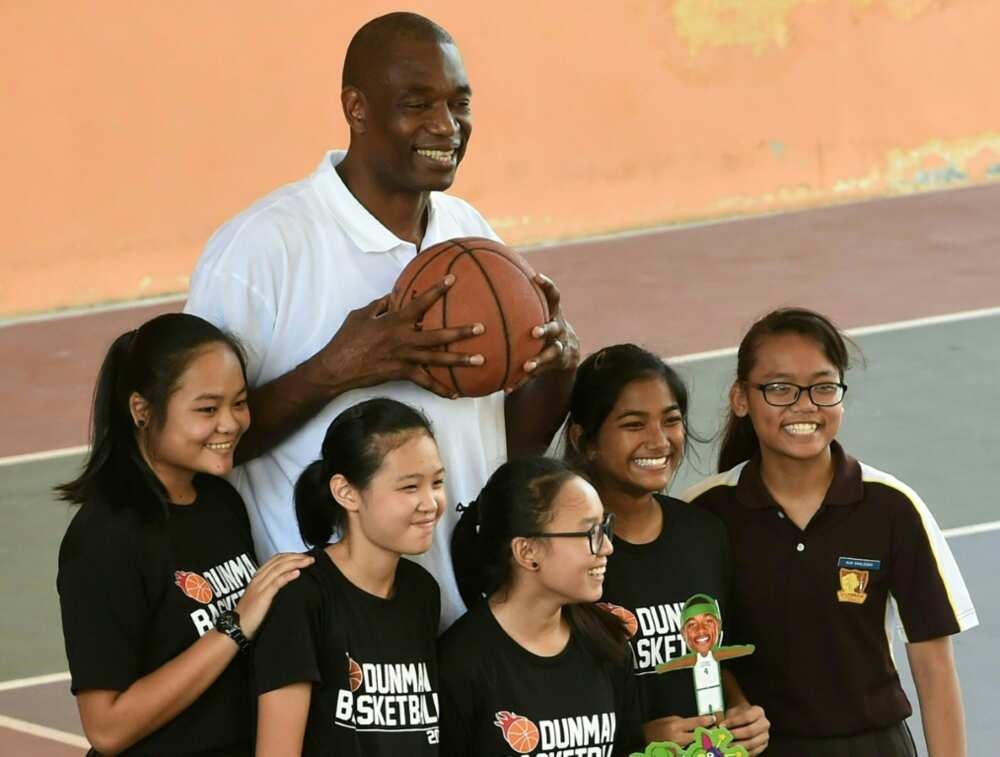 Retired NBA great Dikembe Mutombo -- seen here in 2020 with schoolchildren in Singapore -- is undergoing treatment for a brain tumor
