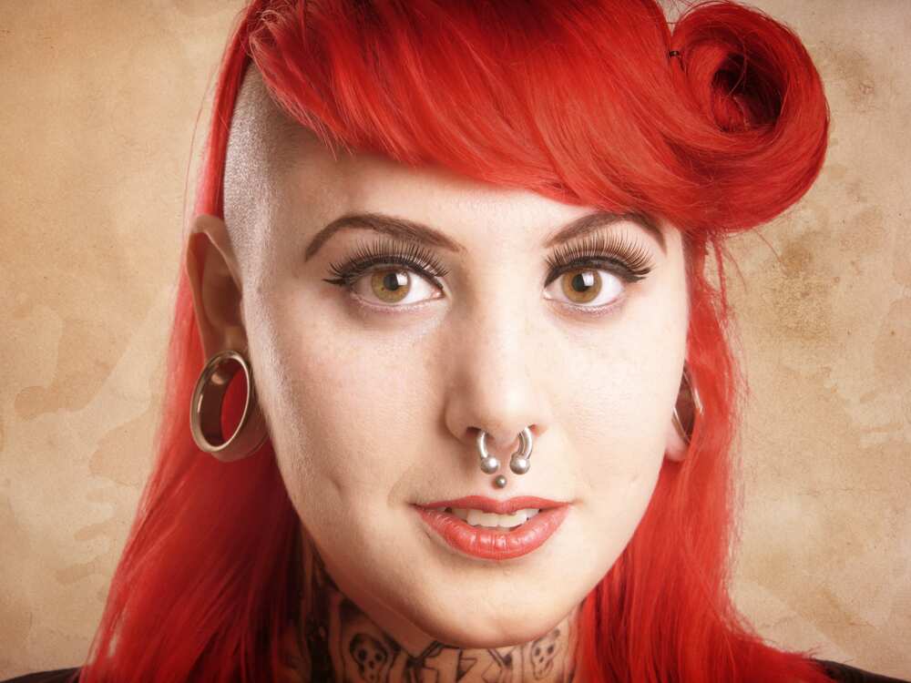 Young woman with side cut, facial piercings and tattoos - with added texture filter effect