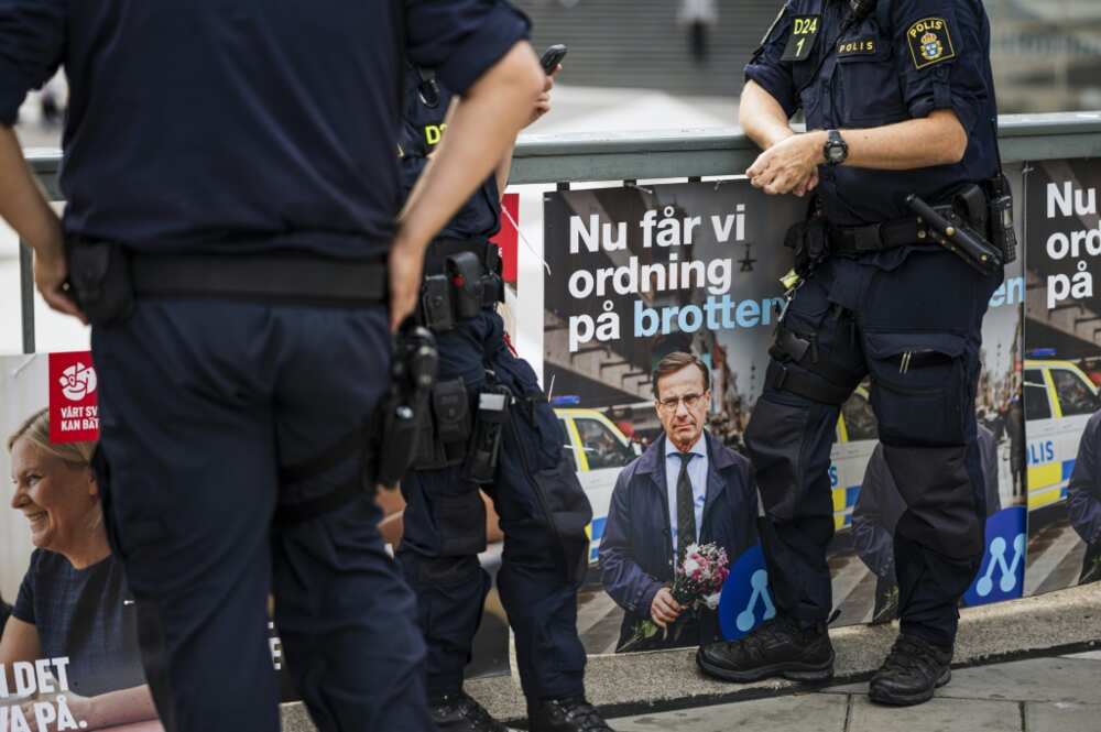 Police officers stand next to election posters in Stockholm. Sweden has struggled to combat escalating gang shootings attributed to battles over the drugs and weapons market