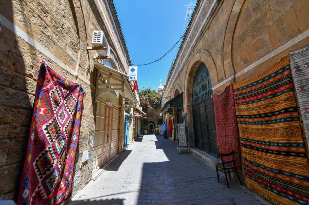 Traditional carpets displayed on the walls around a shop in the ninth-century medina, one of the first cities built after the Muslim conquests of North Africa