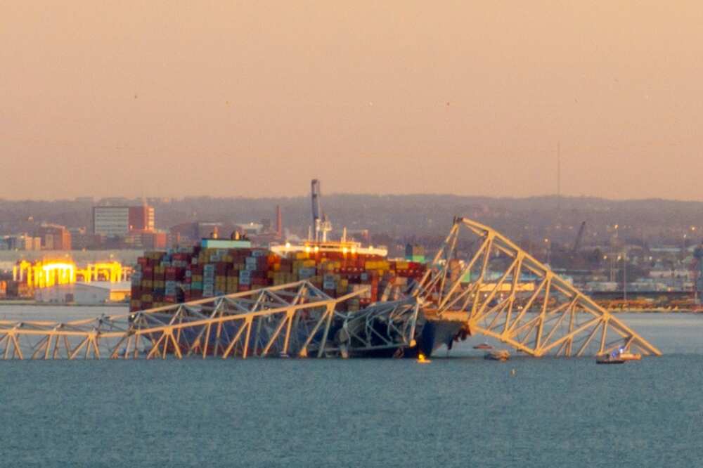 The steel frame of the Francis Scott Key Bridge sits on top of a container ship after it struck the bridge in Baltimore, Maryland, on March 26, 2024