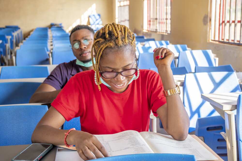 Two young students wearing facemasks and studying in a classroom