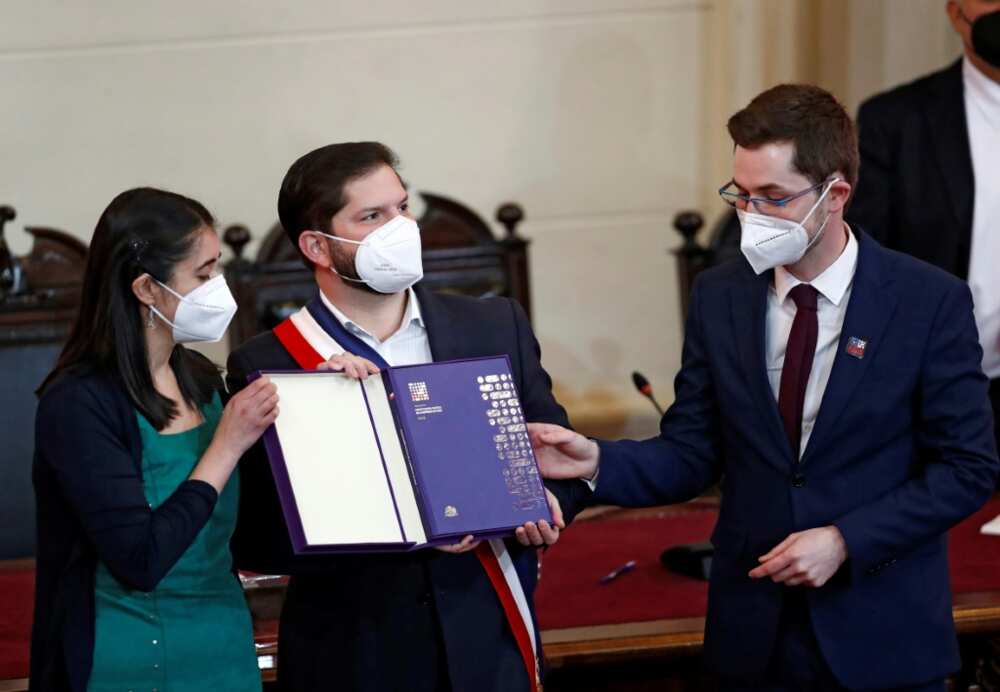 The president and vice-president of Chile's constitutional convention Maria Elisa Quinteros (L) and Gaspar Dominguez (R), respectively, hand the final draft to President Gabriel Boric, at the National Congress in Santiago