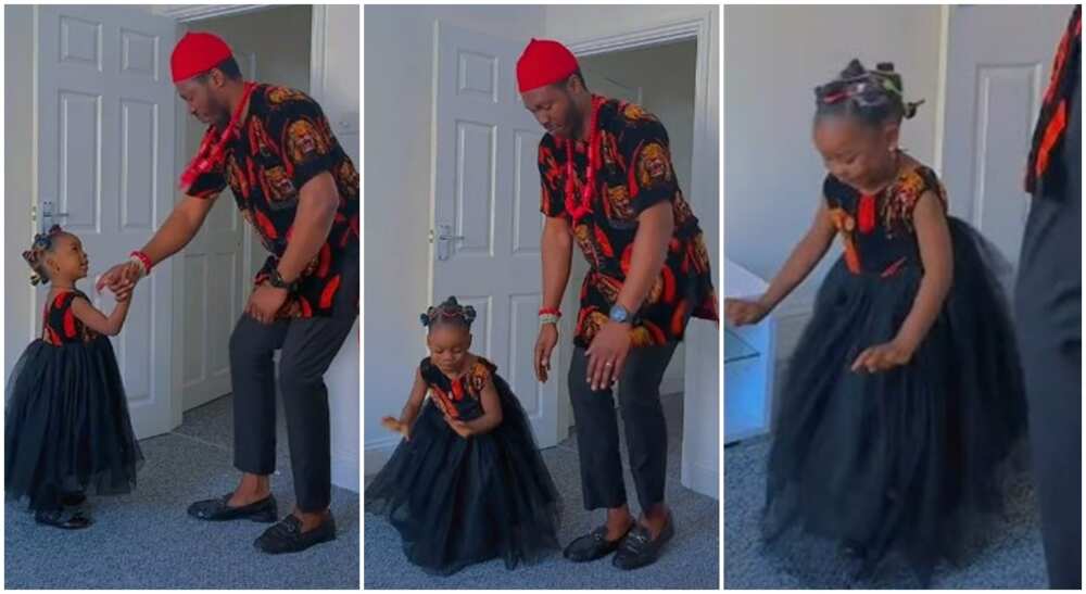 Nigerian man and his little daughter dressed in Isi-Agu material, dancing in a room.
