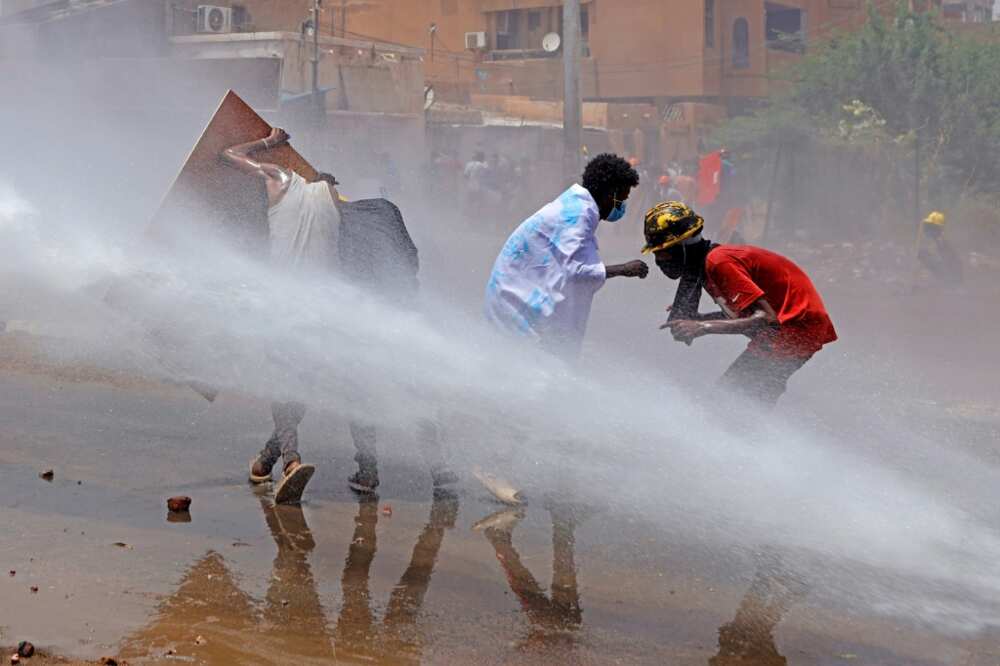 Sudan has seen months of anti-coup protests; here demonstrators take cover as riot police try to disperse them with a water cannon during a demonstration against military rule on June 30
