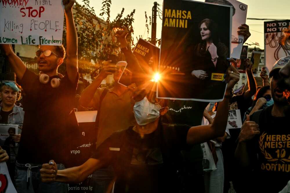 Iranian women in Athens cut their hair in a gesture of solidarity with Amini, brandishig placards reading "say her name!"