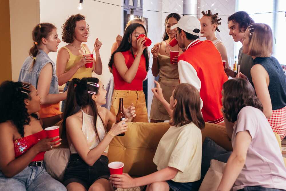 A group of young people at a party talking and drinking from red plastic cups