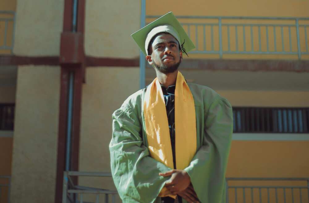 A young man wearing green and yellow graduation gown