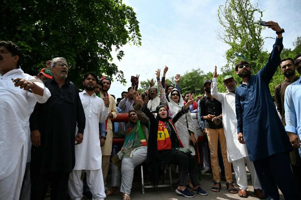 Supporters of former Pakistan prime minister Imran Khan shout outside his home in the capital, Islamabad, after a police probe started into remarks he made against the judiciary at a rally over the weekend