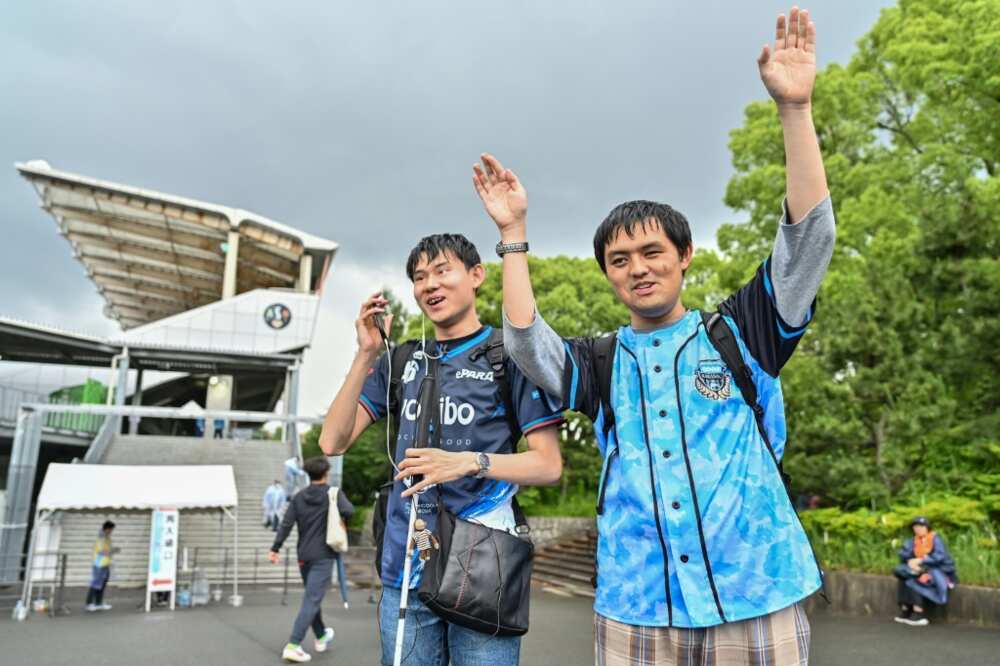 Mashiro (L) cheering with his friend after they arrive at a stadium using an app with ChatGPT for directions