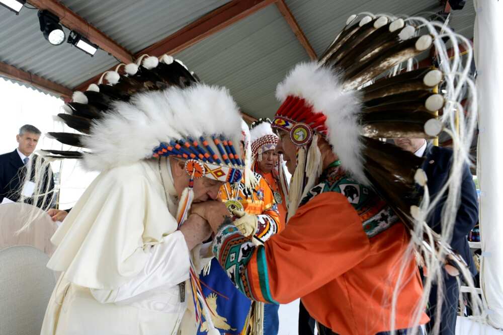 Pope Francis (L), wearing a headdress, kisses the hands of an Indigenous leader at Muskwa Park in Maskwacis, south of Edmonton, western Canada, on July 25, 2022