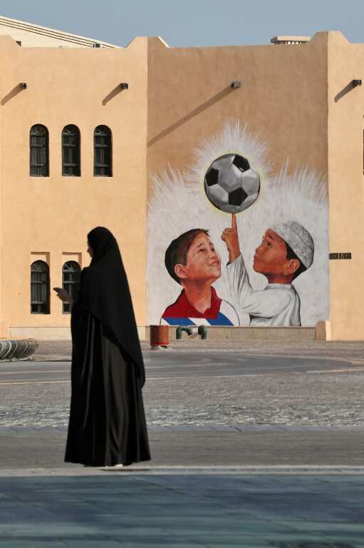 A woman walks past a mural in the Katara Cultural Village, in Qatar's capital Doha, on October 11, 2022 ahead of the FIFA 2022 football World Cup