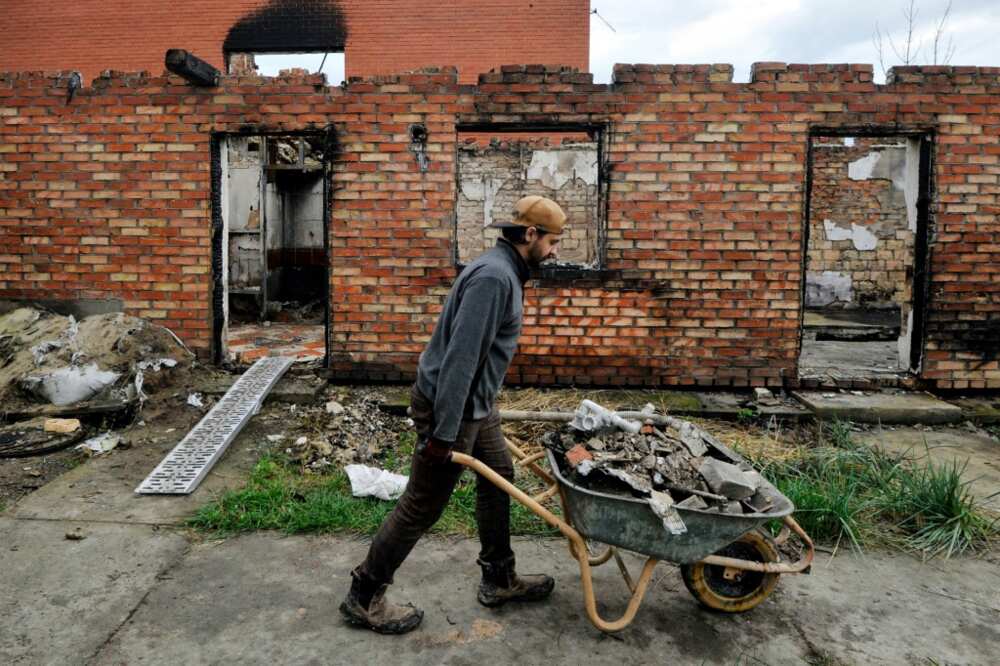 A volunteer clears rubble from a destroyed house in the village of Moshchunon near Kyiv on October 29