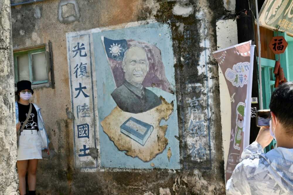 Tourists pose for pictures next to a mural of late Taiwanese president Chiang Kai-shek in Taiwan's Kinmen islands
