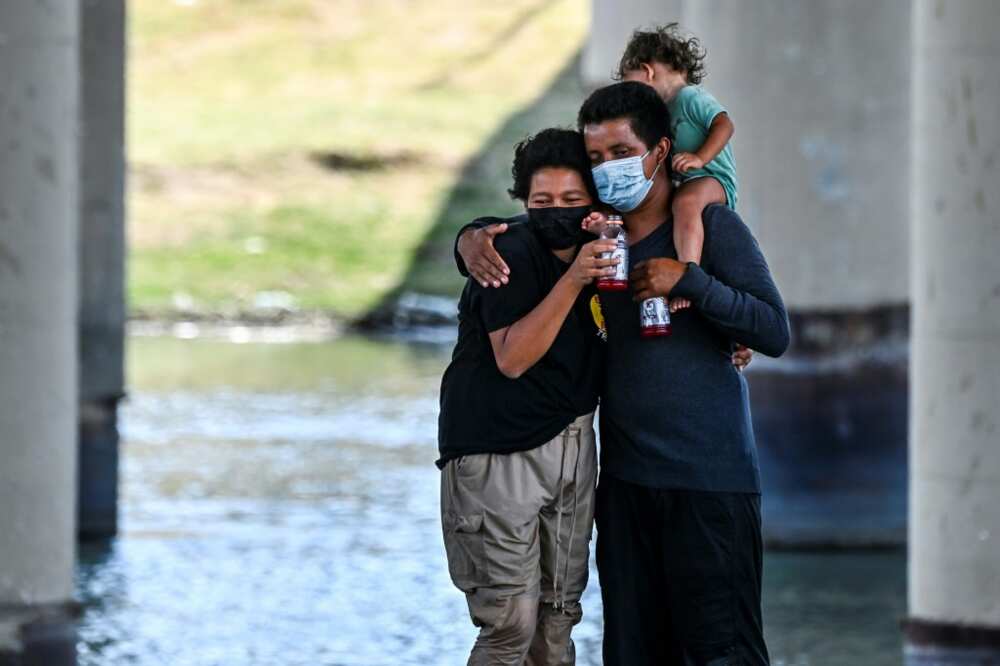 A migrant couple hug after successfully crossing the Rio Grande