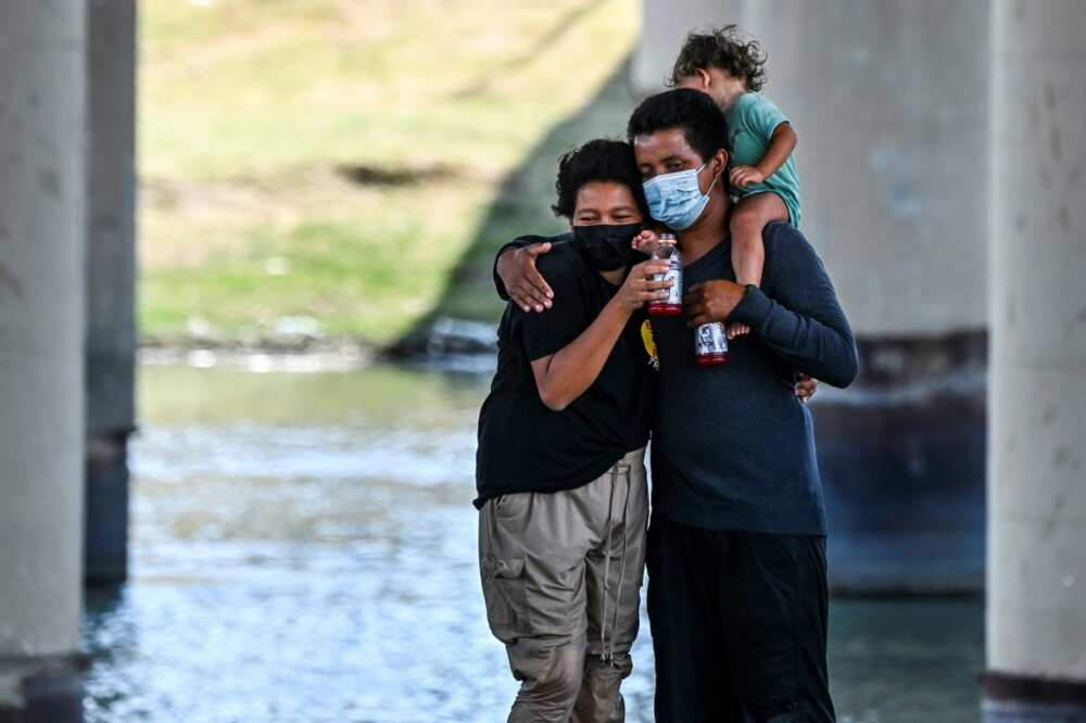 A migrant couple hug after successfully crossing the Rio Grande A migrant couple hug after successfully crossing the Rio Grande