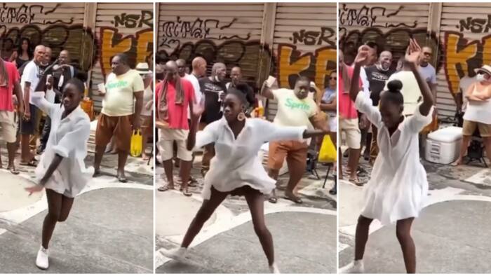 Lady in white dress keeps legs apart, shows off sweet dance moves on street, people fight over her in video