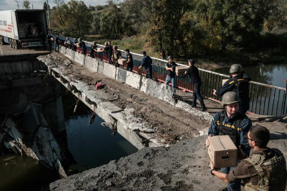 The road deck of the bridge has collapsed into the river and only the pedestrian footpath along the side is passable for troops and civilian refugees crossing between the banks