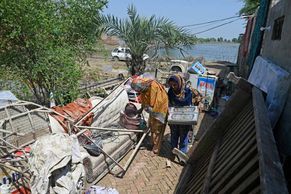 Members of the Hussain family try to salvage their belongings from their flood-damaged home in Fazilpur, Punjab province
