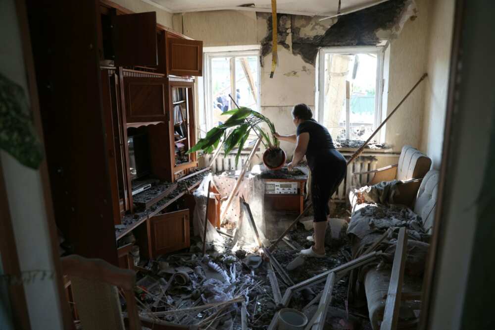 A woman cleans debris in her house after a Russian missile strike on the Donetsk region town of Konstantinovka