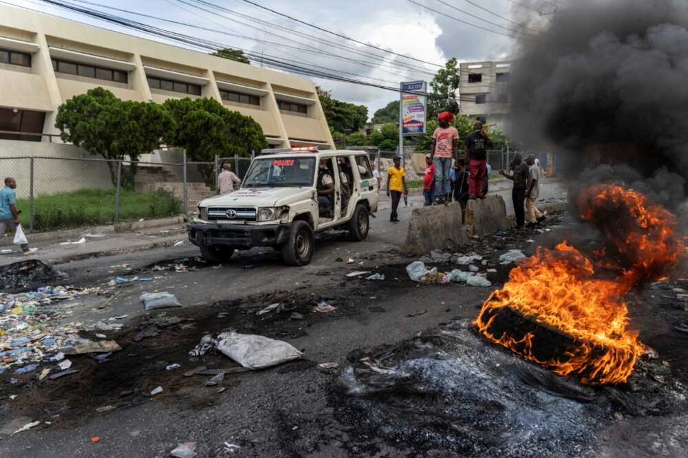 A police car drives past a burning tire as demonstrators protest against a government-requested international military force in Port-au-Prince, Haiti, on October 24, 2022