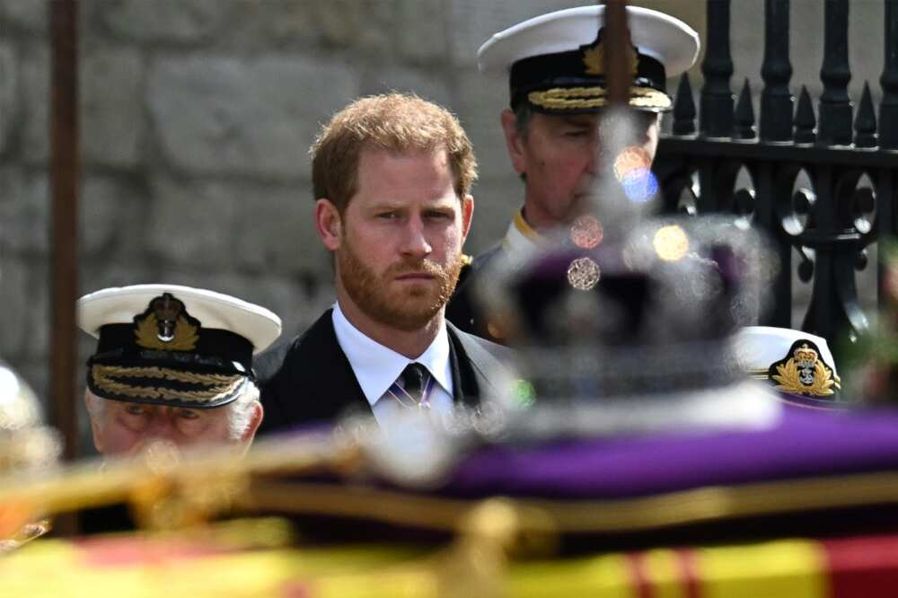 Britain's Prince Harry, Duke of Sussex, looks at the coffin of Queen Elizabeth II, draped in the Royal Standard, as it travels from Westminster Abbey to Wellington Arch in London on September 19, 2022, after her funeral service