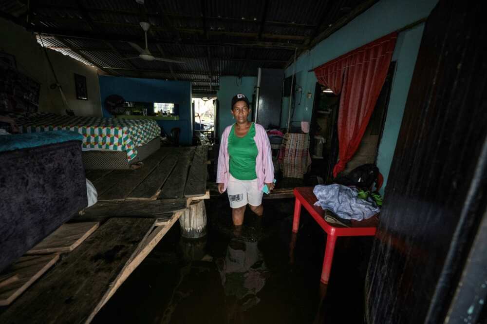 Rosiris Berrio moves around her flooded home, where beds and furniture has been placed on a system of raised planks