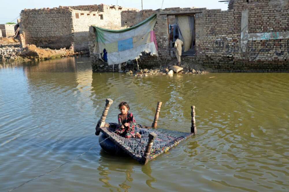 A girl sits on a cot as she crosses a flooded street at Sohbatpur in Jaffarabad district of Balochistan province on October 4, 2022