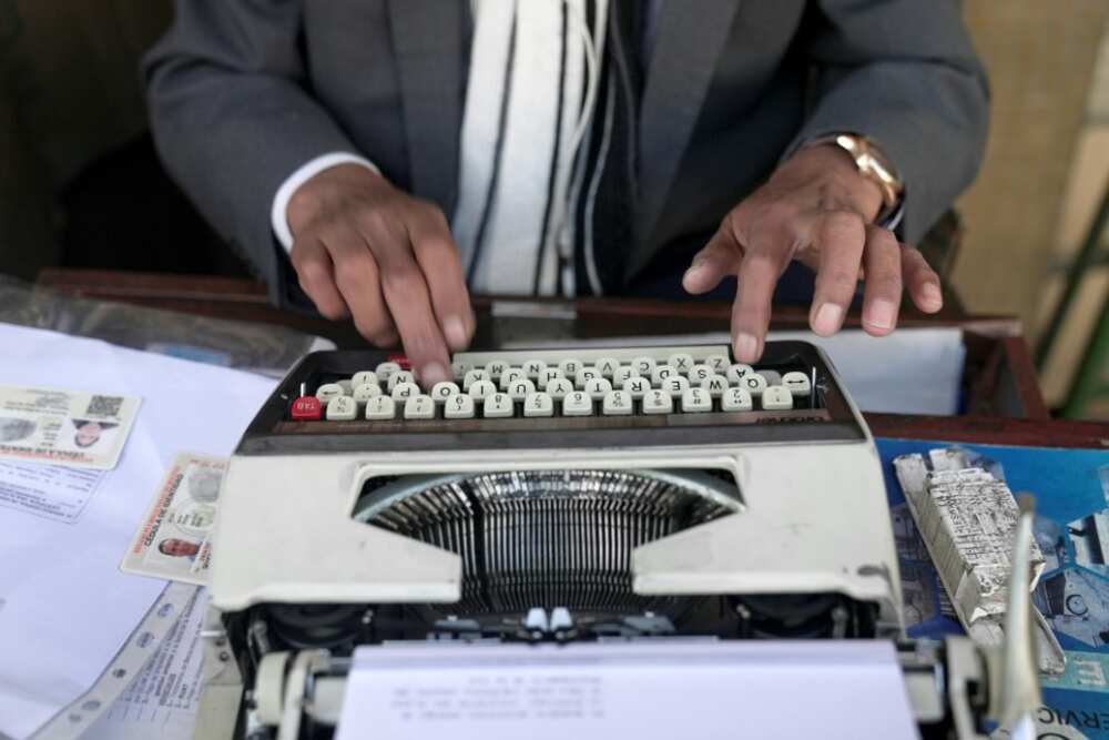Rogelio Condori uses a typewriter on the street in La Paz, Bolivia to fill out paperwork for clients