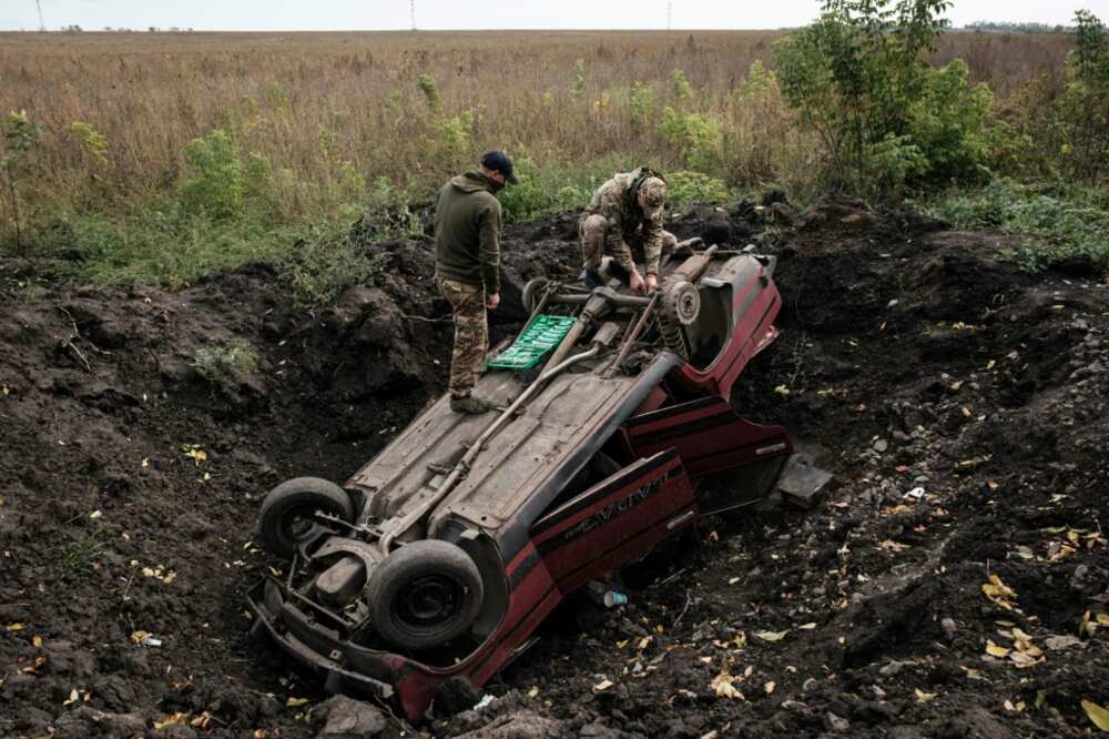 Ukrainian soldiers inspect a destroyed car in the Kharkiv region where Kyiv's forces have recently reclaimed swathes of territory