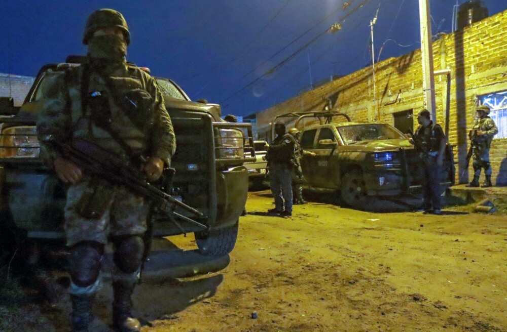 Mexican troops stand guard at the scene of a gun battle between police and suspected criminals in El Salto in western Mexico