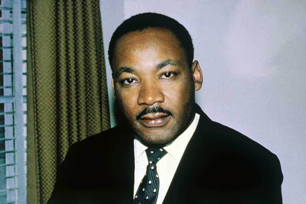 Reverend Dr. Martin Luther King in a black suit, white shirt and a black and white tie
