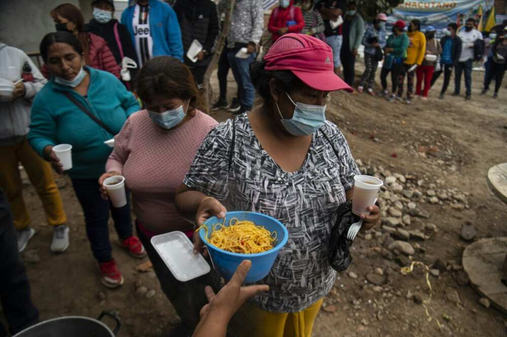 People queue for food at a soup kitchen in Peru