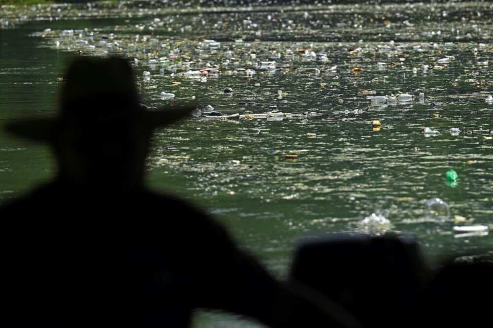 A fisherman looks out over the carpet of plastic waste covering the Cerron Grande reservoir in Potonico, El Salvador