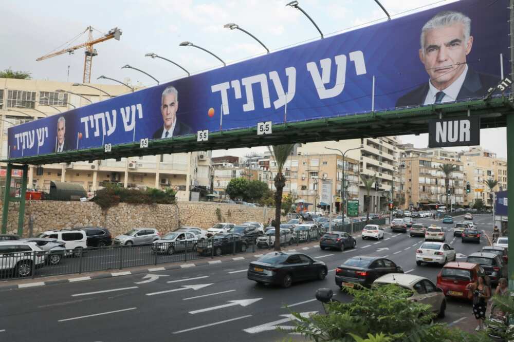 Cars drive on a highway beneath electoral billboards for Israeli caretaker Prime Minister Yair Lapid in Tel Aviv, on October 23, 2022