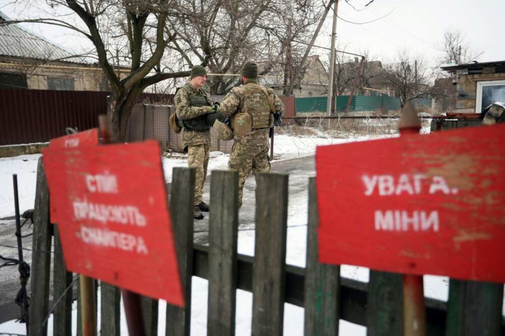 Ukrainian soldiers stand guard near signs reading 'Beware of landmines'