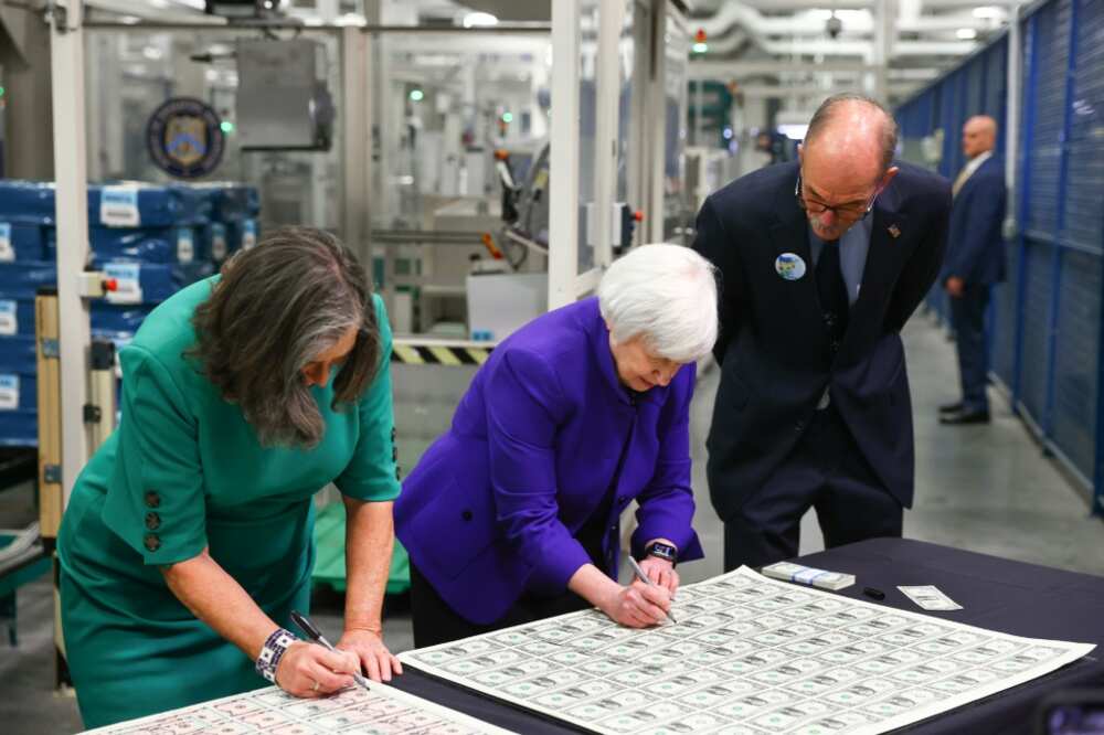 US Treasury Secretary Janet Yellen (C) and Treasurer Marilynn Malerba (L) sign $1 bills at the Bureau of Engraving and Printing facility in Fort Worth on December 8, 2022