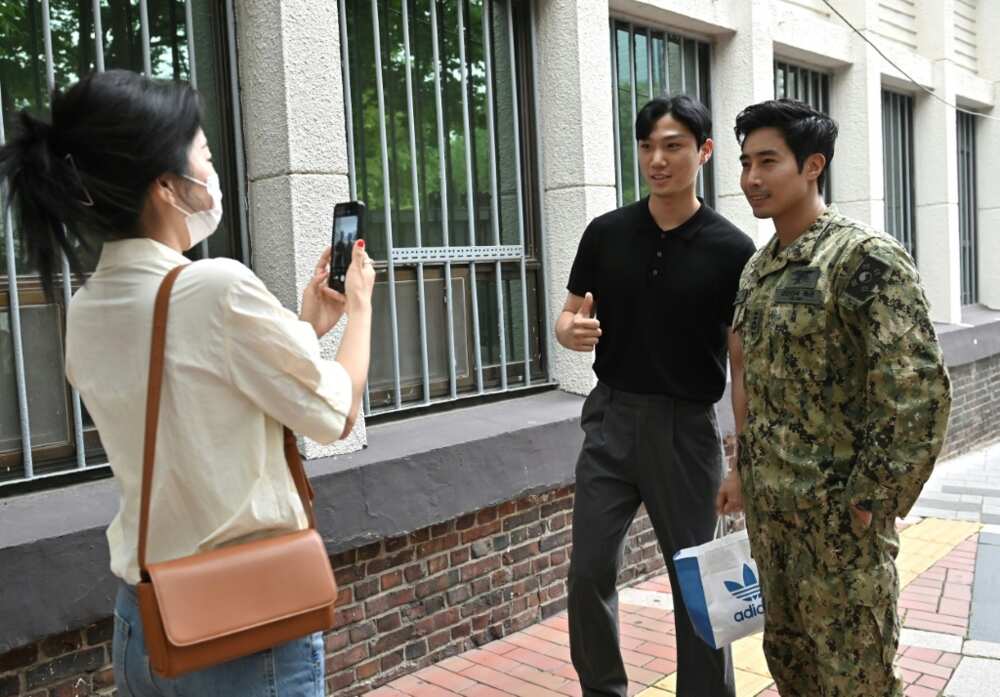 Former South Korean Navy SEAL turned YouTuber Ken Rhee (R) poses for a photo with a fan on a street in Seoul
