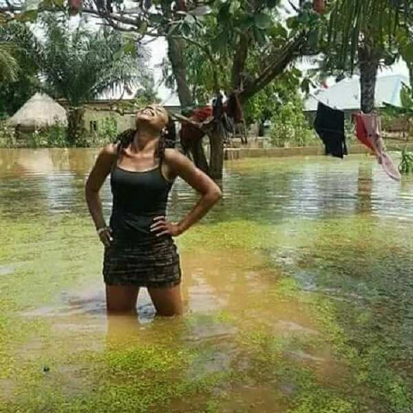 Young lady strikes a pose in front of her house as flood overtakes it in Benue state (photos)