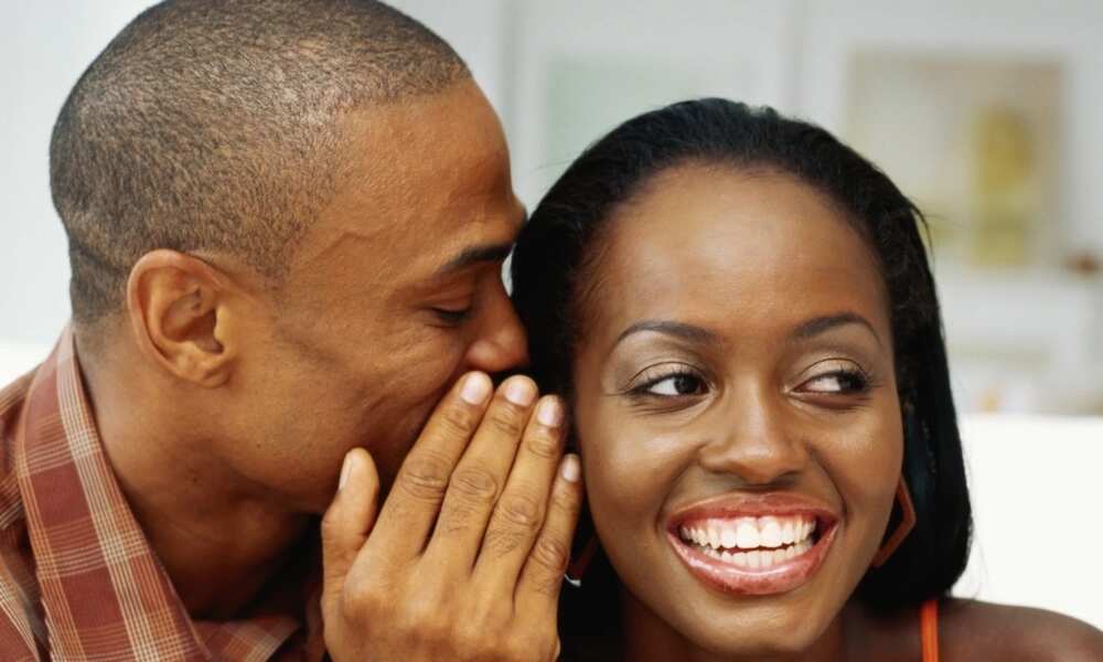Man whispering something funny into his lady's ear