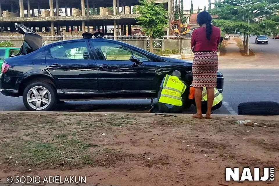 Nigerian police officers help a lady in distress, fix her car in Abuja (photo)